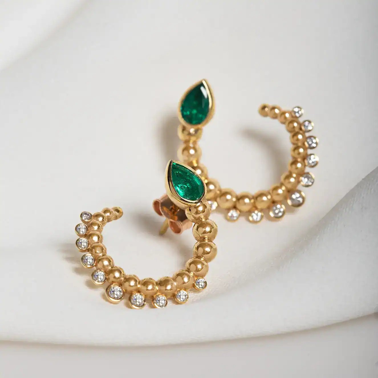 Gold hoop earrings with emerald-cut green stones and diamonds